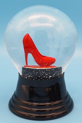 Schneekugel mit rotem Stöckelschuh auf schwarzem Sockel