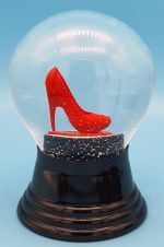 Schneekugel mit rotem Stöckelschuh auf schwarzem Sockel